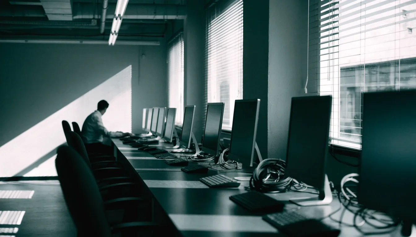 Working IT lab at midday with workstations and a person seated at the far end
