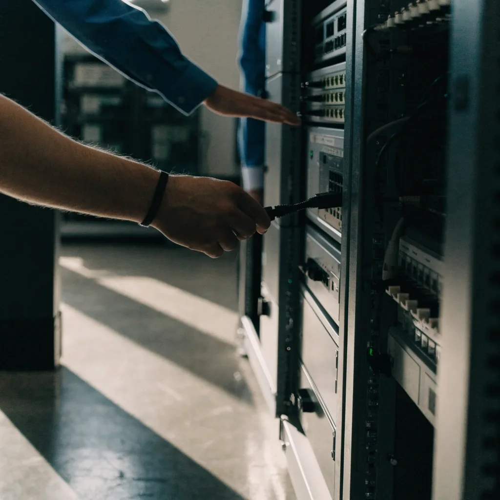 Network switch racks and bundled cable runs inside a dim server room at midday